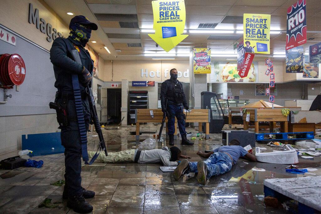 Police stand over arrested suspect looters in a shopping centre in Alexandra township, Johannesburg, South Africa, July 12. Photo: AP