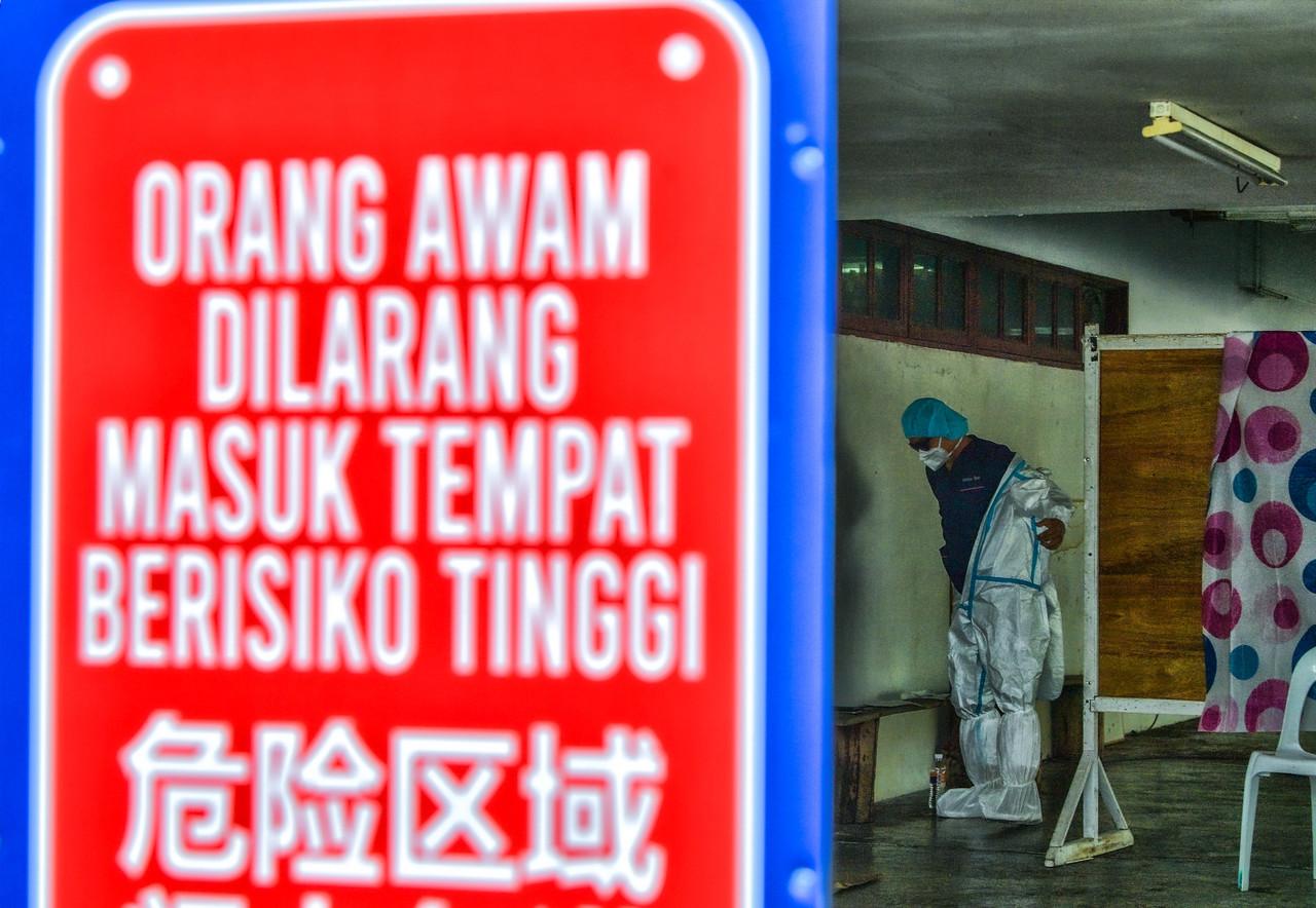 A frontline worker puts on personal protective equipment before screening people for Covid-19 at the one-stop centre at Dewan Masyarakat Kuching in Sarawak. Photo: Bernama