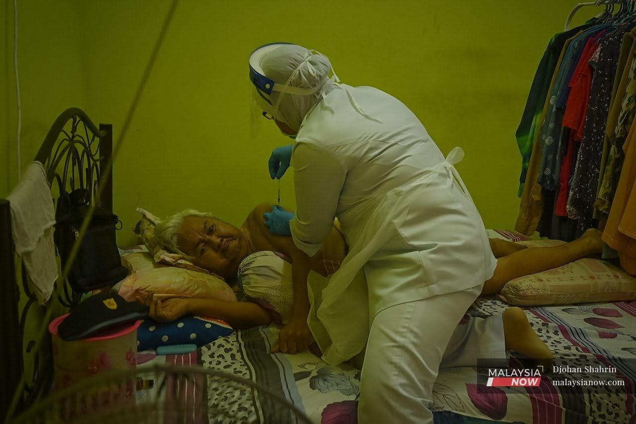 A nurse gives a shot of Covid-19 vaccine to a bedridden person under the Sabak Bernam vaccination outreach programme in Sungai Besar, Kuala Selangor.