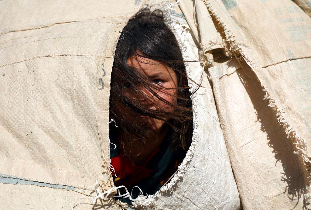 An internally displaced Afghan girl who fled her home due to fighting between the Taliban and Afghan security personnel, peers from her makeshift tent at a camp on the outskirts of Mazar-e-Sharif, northern Afghanistan, July 8. Photo: AP