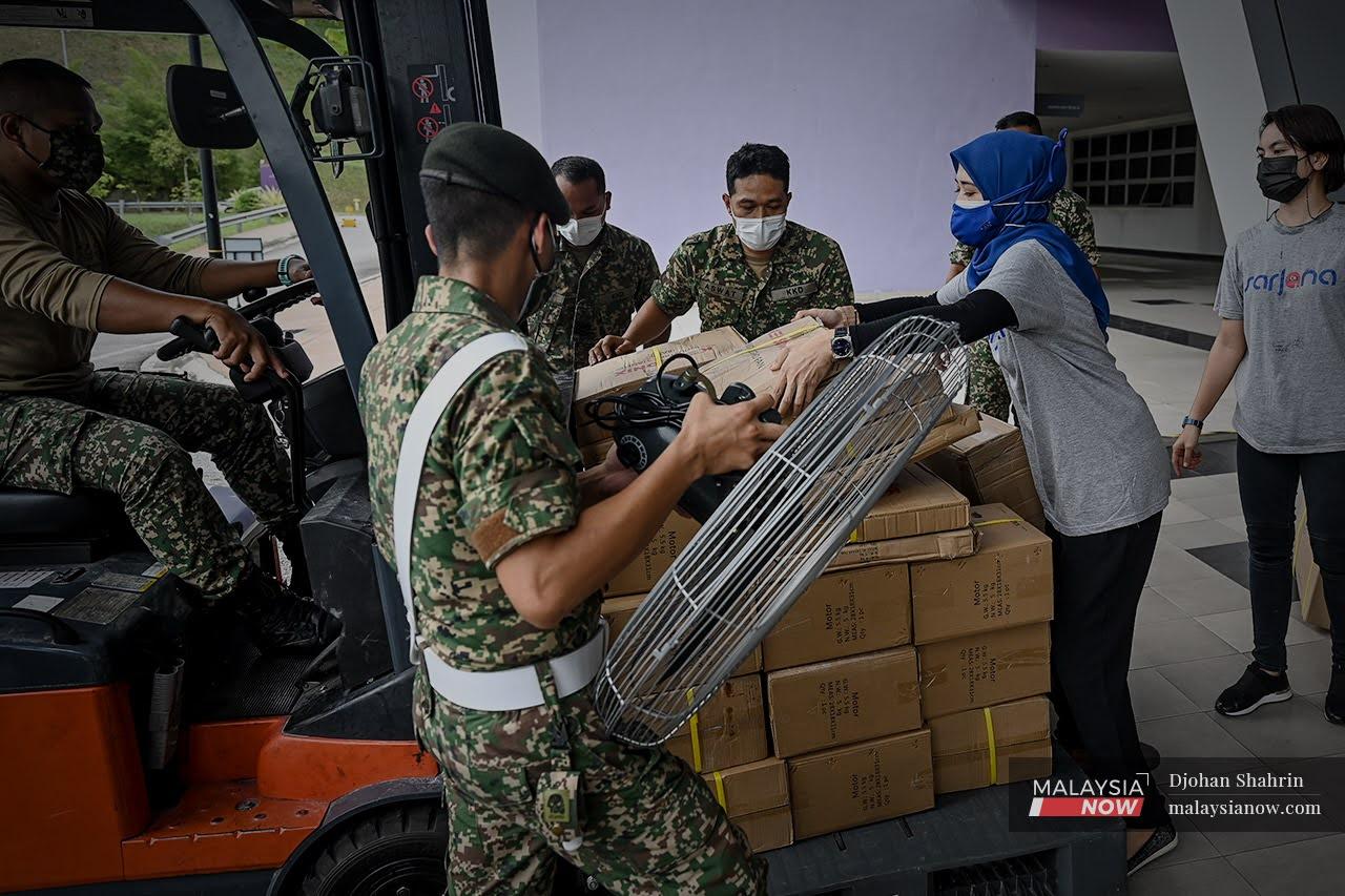 Seorang sukarelawan dari Pertubuhan Sukarelawan Jalinan Nasional melihat anggota tentera menyusun sumbangan berupa kipas industri di atas 'forklift' selepas diserahkan kepada pihak Hospital Tentera Tuanku Mizan untuk digunakan pesakit Covid-19.