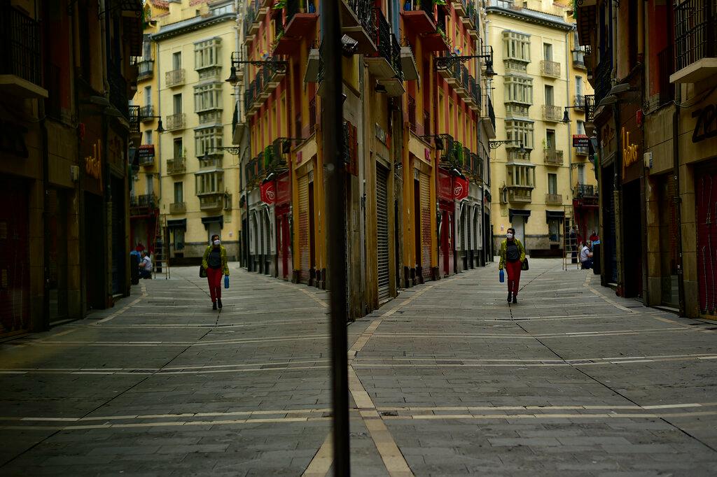 A woman wearing a face mask to prevent the spread of the coronavirus is reflected in glass while walking along an empty street in Pamplona, northern Spain, during the country's lockdown on May 1, 2020. Photo: AP