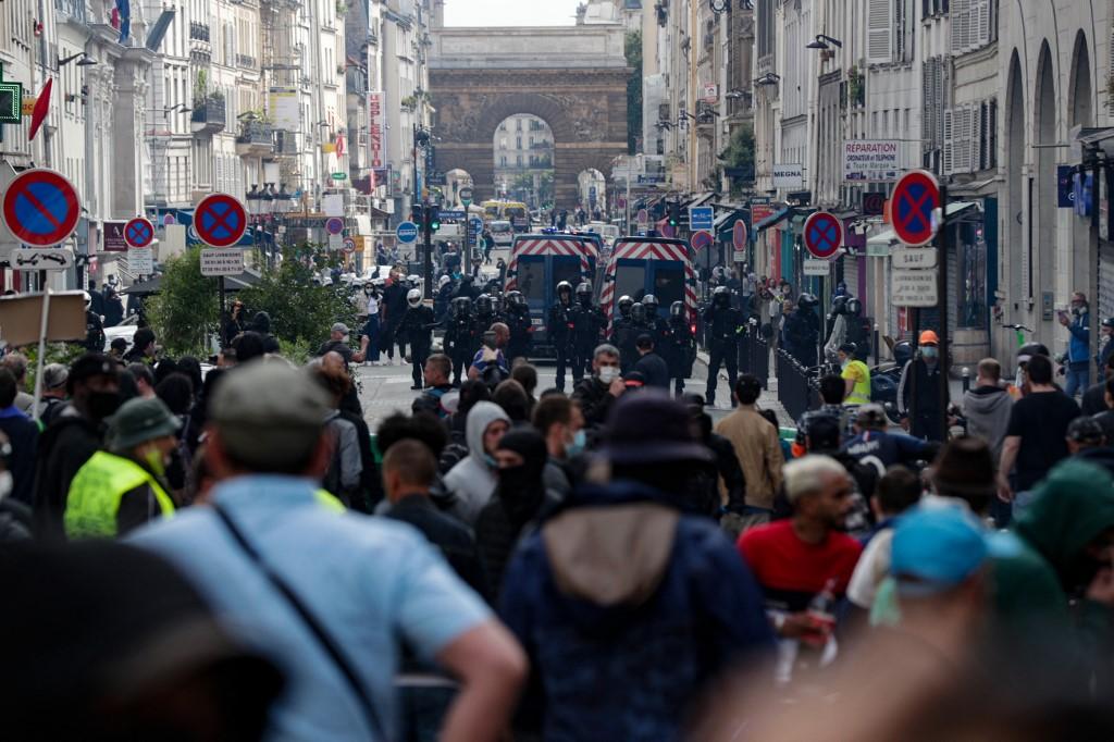Police face demonstrators in central Paris on July 14, during a protest against a governmental decision to impose Covid-19 tests for unvaccinated people who want to eat in restaurants or take long-distance trips, as the country looks to avoid a surge in more contagious Delta cases. Photo: AFP