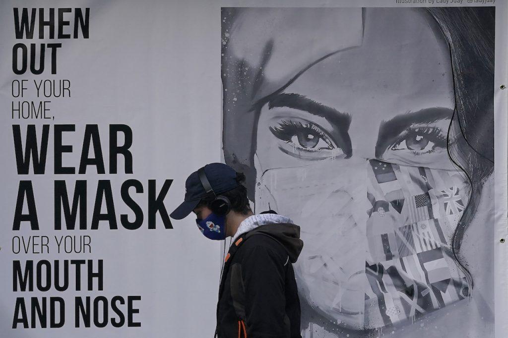 A youth walks past a mural reminding people to wear face masks in California, in this December 2020 file photo. Los Angeles is the first large US metropolis to reimpose the use of face masks at indoor public establishments to help contain the pandemic. Photo: AP