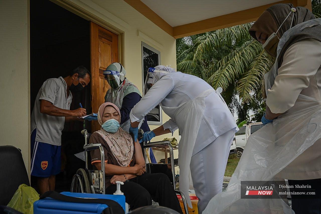 Team Outreach Program Imunisasi Covid-19 Kebangsaan melakukan vaksinasi kepada seorang suri rumah yang duduk di kerusi roda di Sungai Besar, Kuala Selangor.Usaha outreach tertumpu kepada golongan yang uzur disebabkan penyakit yang dihidapi mereka, kumpulan kesihatan ini bergerak dari rumah ke rumah dengan memberi perkhidmatan suntikan vaksin kepada mereka yang berdaftar.
