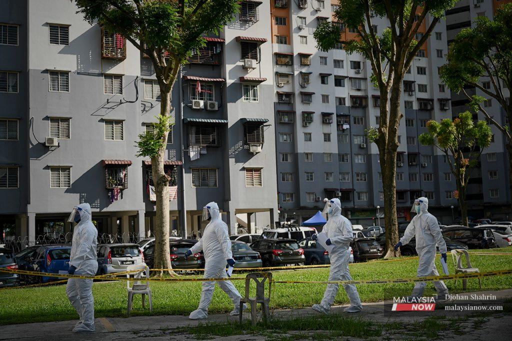 Health workers in personal protective equipment head to the site of a targeted screening for Covid-19 at an apartment area in Selangor placed under enhanced movement control order.