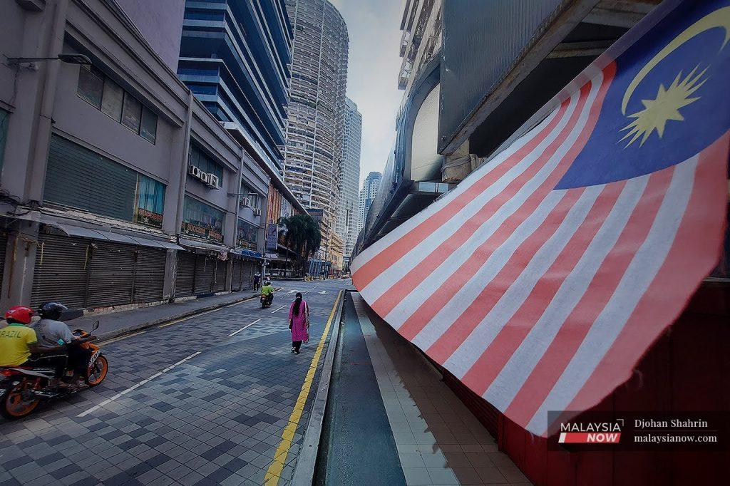 A Malaysian flag flutters over a row of shops in Kuala Lumpur which were closed under the movement restrictions imposed to curb the spread of Covid-19.