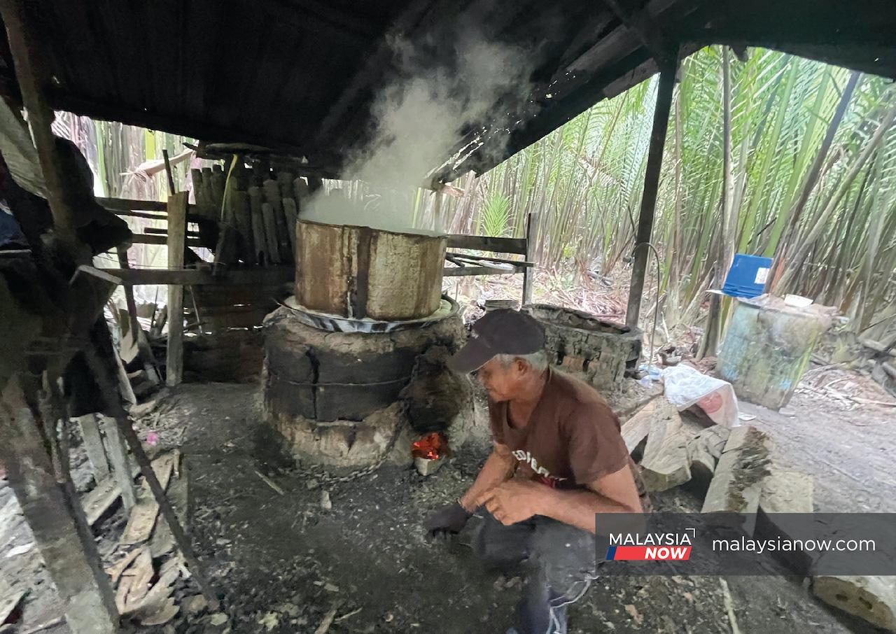Mahli Ramli boils the sap of the nipa palm tree over a wood fire in a small hut near the mangrove forest at Kampung Pinggan Jaya.