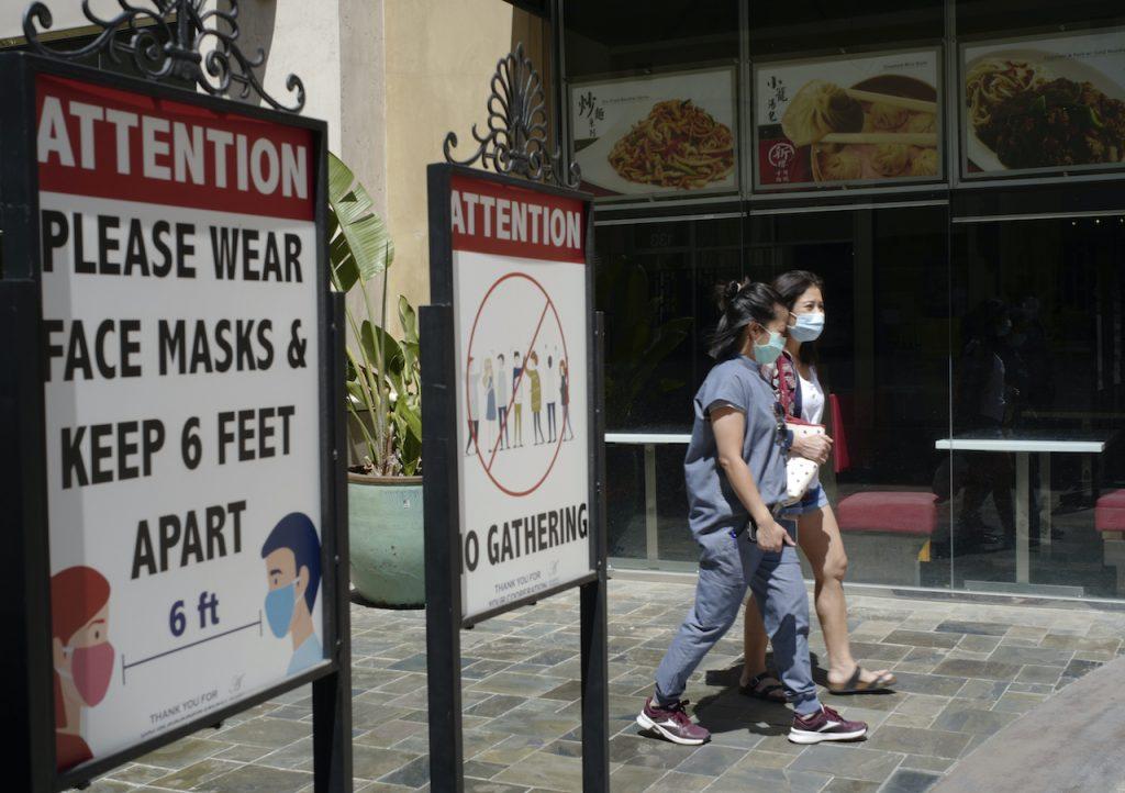 In this June 11 file photo, customers wear face masks in an outdoor mall with closed business amid the Covid-19 pandemic in Los Angeles, California. Photo: AP
