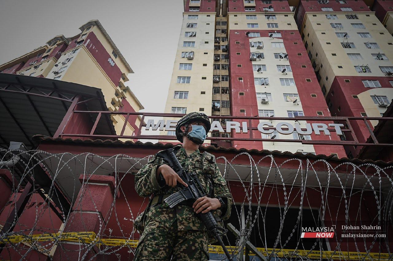 Seorang anggota tentera berdiri di hadapan rumah pengawal yang dipasang duri kawat ketika kawasan ketika pelaksanaan perintah kawalan pergerakan diperketatkan di Petaling Jaya awal bulan ini.
