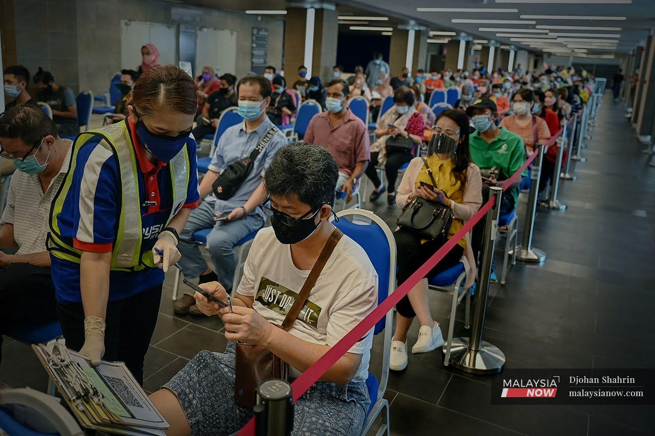 Volunteers help people register for Covid-19 vaccination at the Axiata Arena Bukit Jalil vaccination centre.