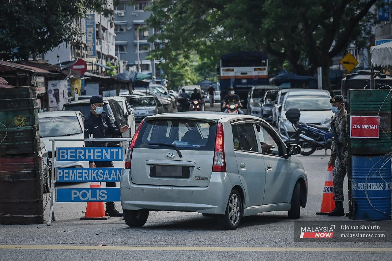 Dua anggota Polis dan Tentera membuat pemeriksaan ke atas kenderaan yang ingin masuk ke Taman Bukit Angkasa di Pantai Dalam sepanjang kawasan itu dikenakan PKPD.