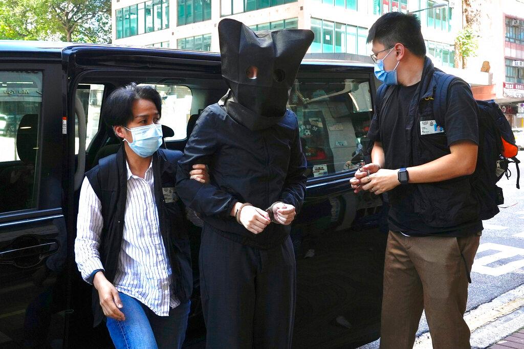 A hooded suspect is accompanied by police officers to search evidence at office in Hong Kong, July 22. Hong Kong's national security police have arrested five people from a trade union of the General Association of Hong Kong Speech Therapists on suspicion of conspiring to publish and distribute seditious material, in the latest arrests made amid a crackdown on dissent in the city. Photo: AP