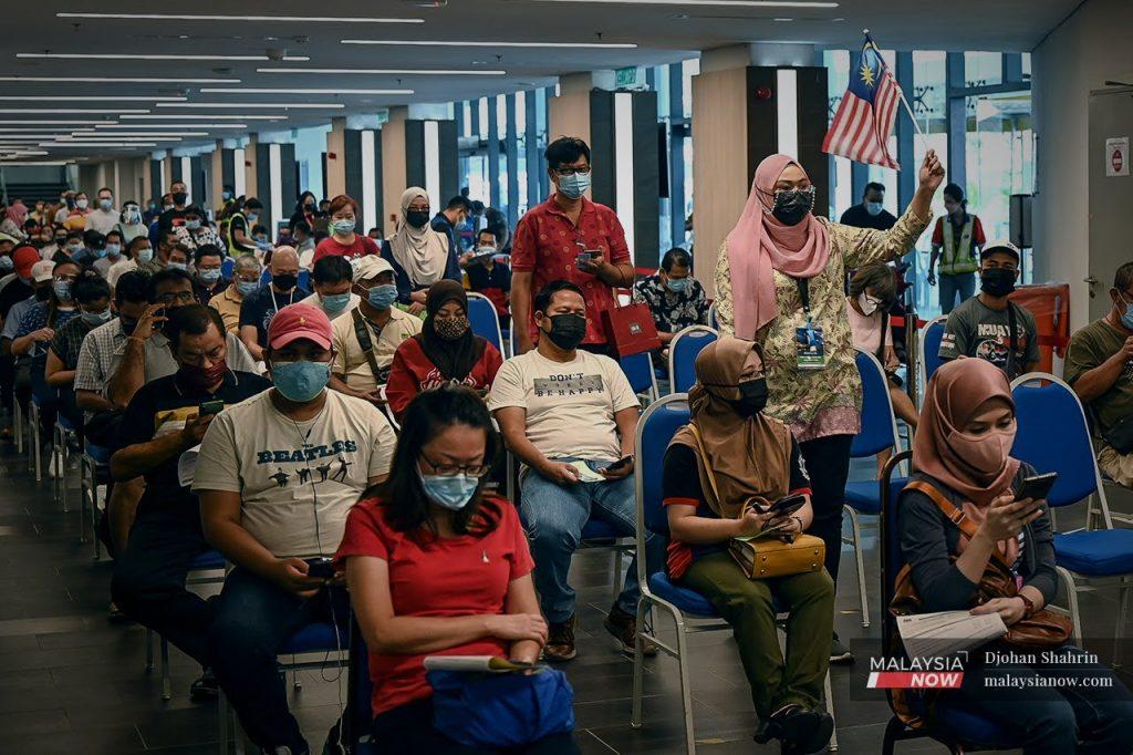 People wait for their turn to be administered a shot of Covid-19 vaccine at the Axiata Arena Bukit Jalil vaccination centre.