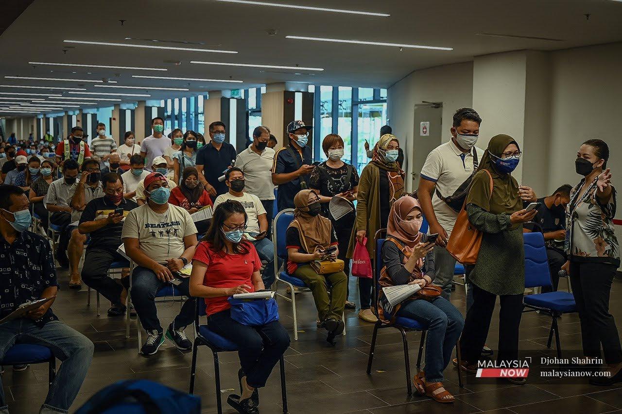 Penerima vaksin yang menghadiri janji temu menunggu giliran mereka untuk ke stesen vaksinasi di Axiata Arena Bukit Jalil.