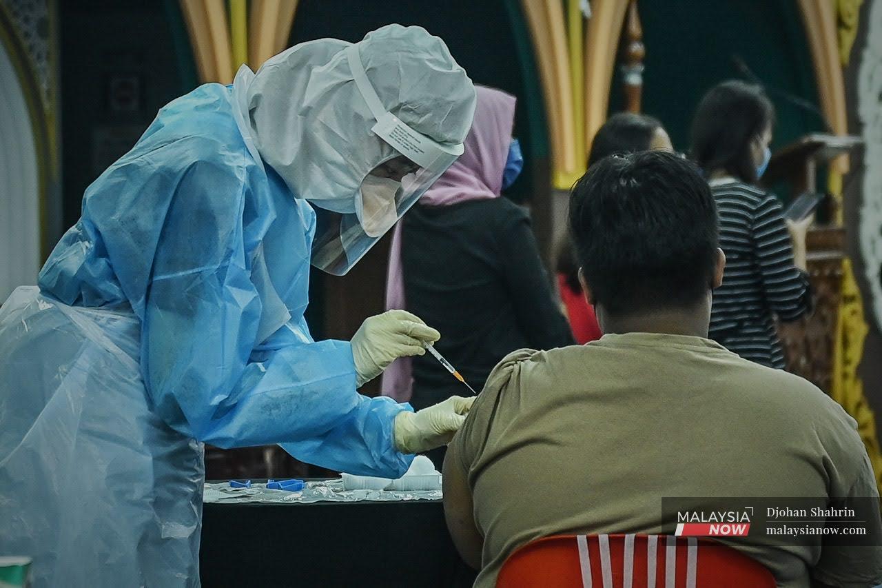 Petugas kesihatan memberikan vaksin Pfizer Bio-NTech kepada penduduk yang dikenakan PKPD di Mentari Court, Petaling Jaya.