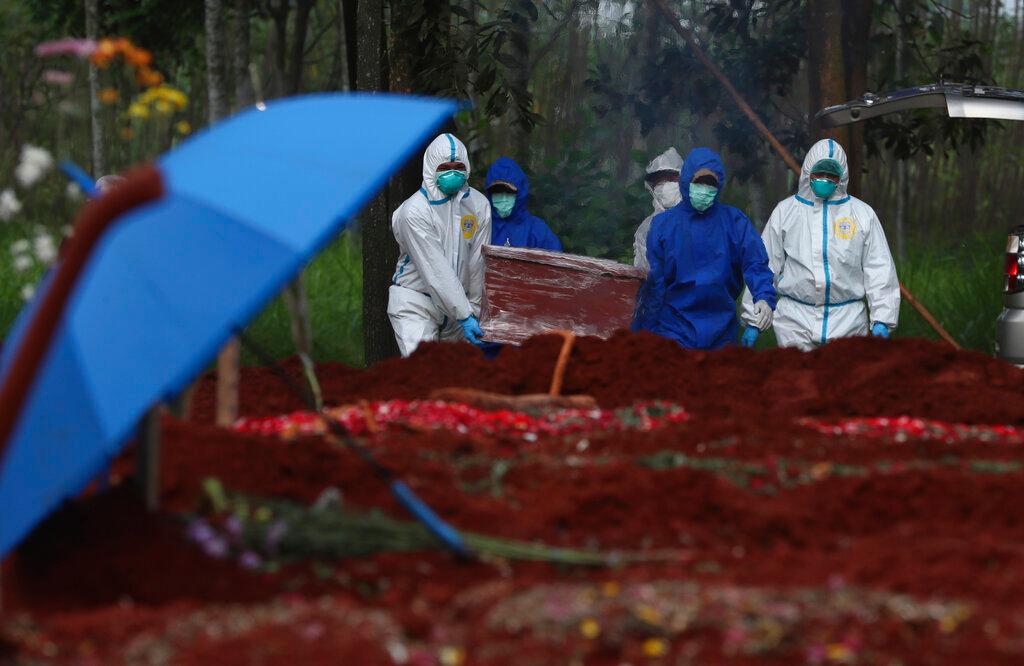 Workers in protective suits carry the coffin of a Covid-19 victim to a grave for burial at Cipenjo cemetery in Bogor, West Java, Indonesia on July 14. Photo: AP