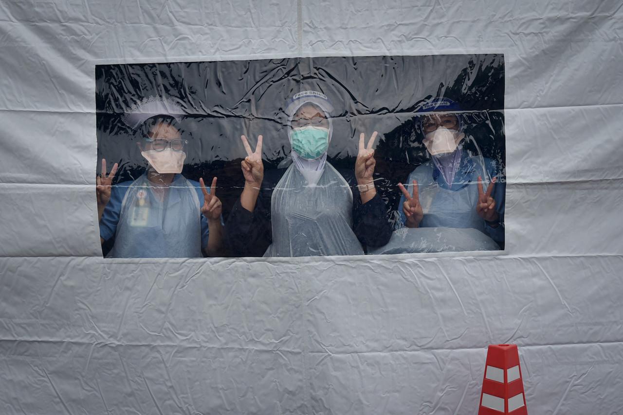 Health workers hold up peace signs at the drive-thru vaccination centre at the Labuan international campus of Universiti Malaysia Sabah. Photo: Bernama