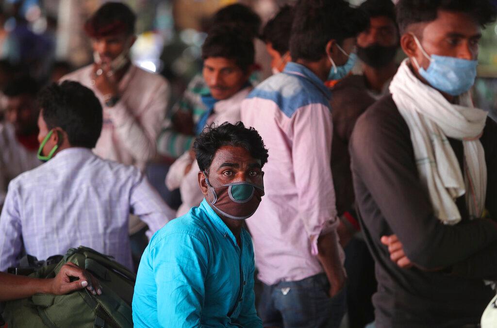 Migrant labourers wearing masks as a precaution against the coronavirus wait for transportation at a bus station in Jammu, India, March 26. Migrant workers often use trains and buses, cheap modes of transport in India, to go home when they get a break from work. Photo: AP