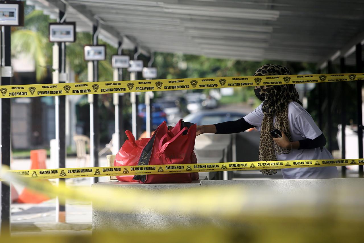A woman places a bag of food for her family members at a specially designated area in the Taman Chembong Utama area in Rembau which is under enhanced movement control order. Photo: Bernama