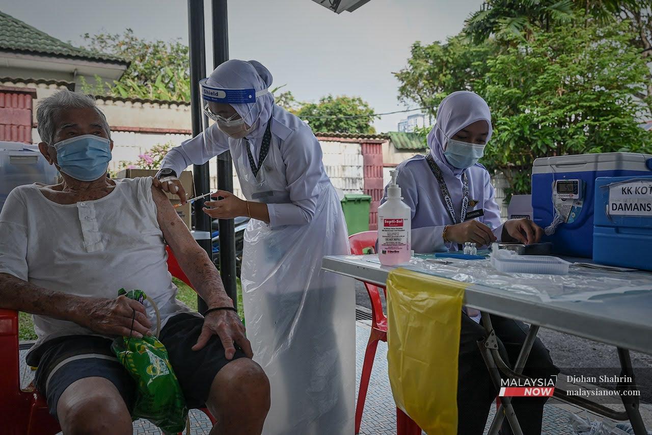 Health workers administer a dose of Pfizer vaccine to a senior citizen at a home in Petaling Jaya, Selangor.