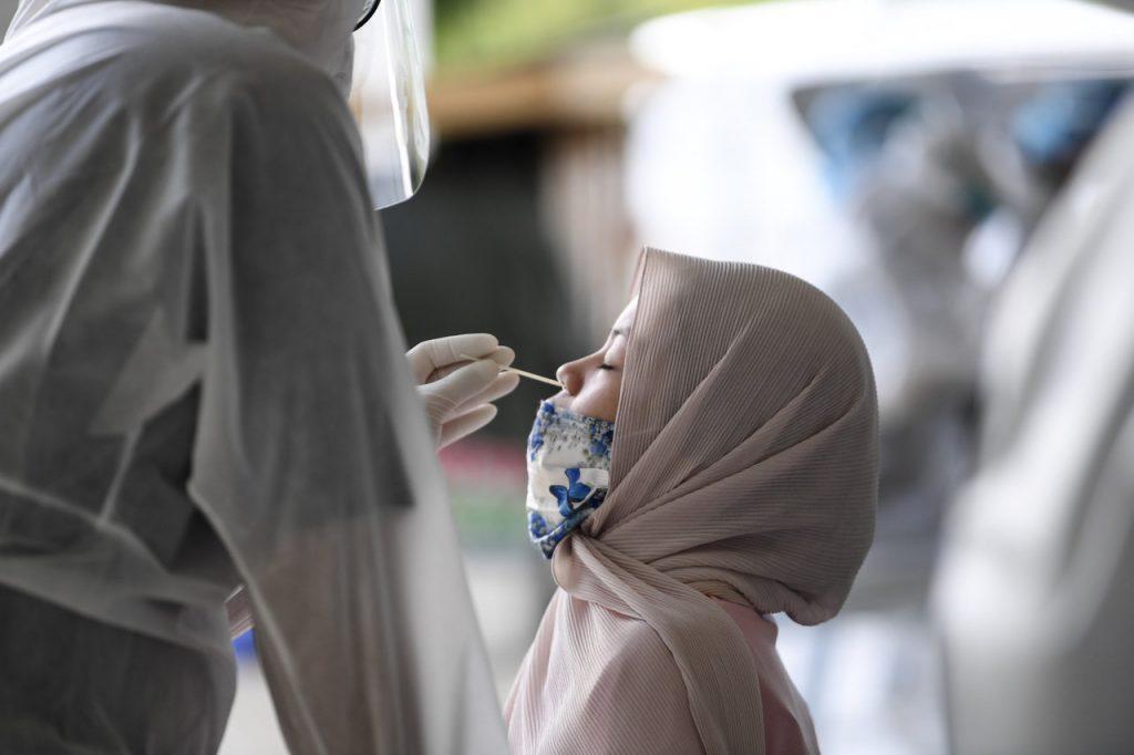 Petugas kesihatan melakukan swab daripada seorang wanita di Sandakan, Sabah untuk diuji Covid-19. Gambar: Bernama