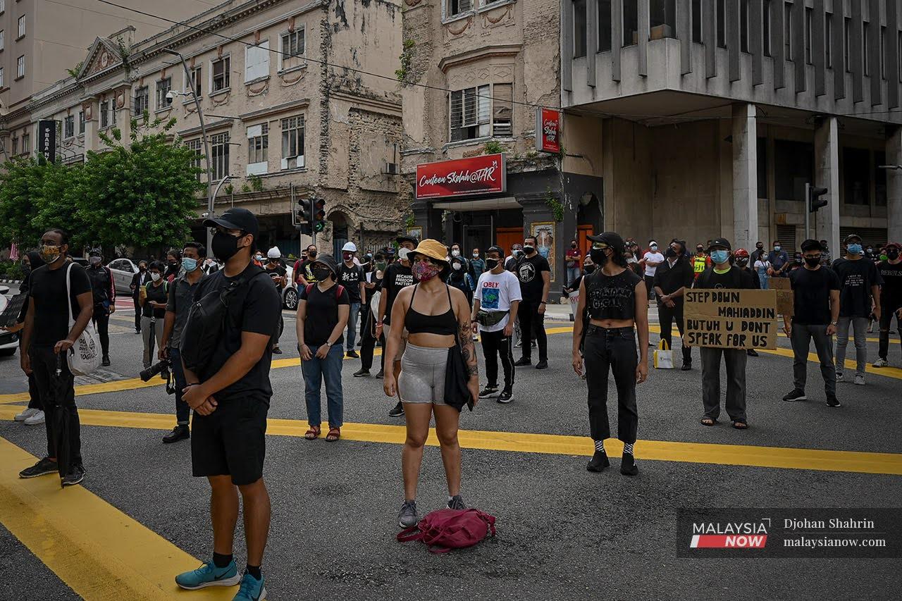 Peserta himpunan #Lawan membawa sepanduk dengan berpakaian hitam berjalan di Jalan Tun Perak menuju ke Dataran Merdeka.