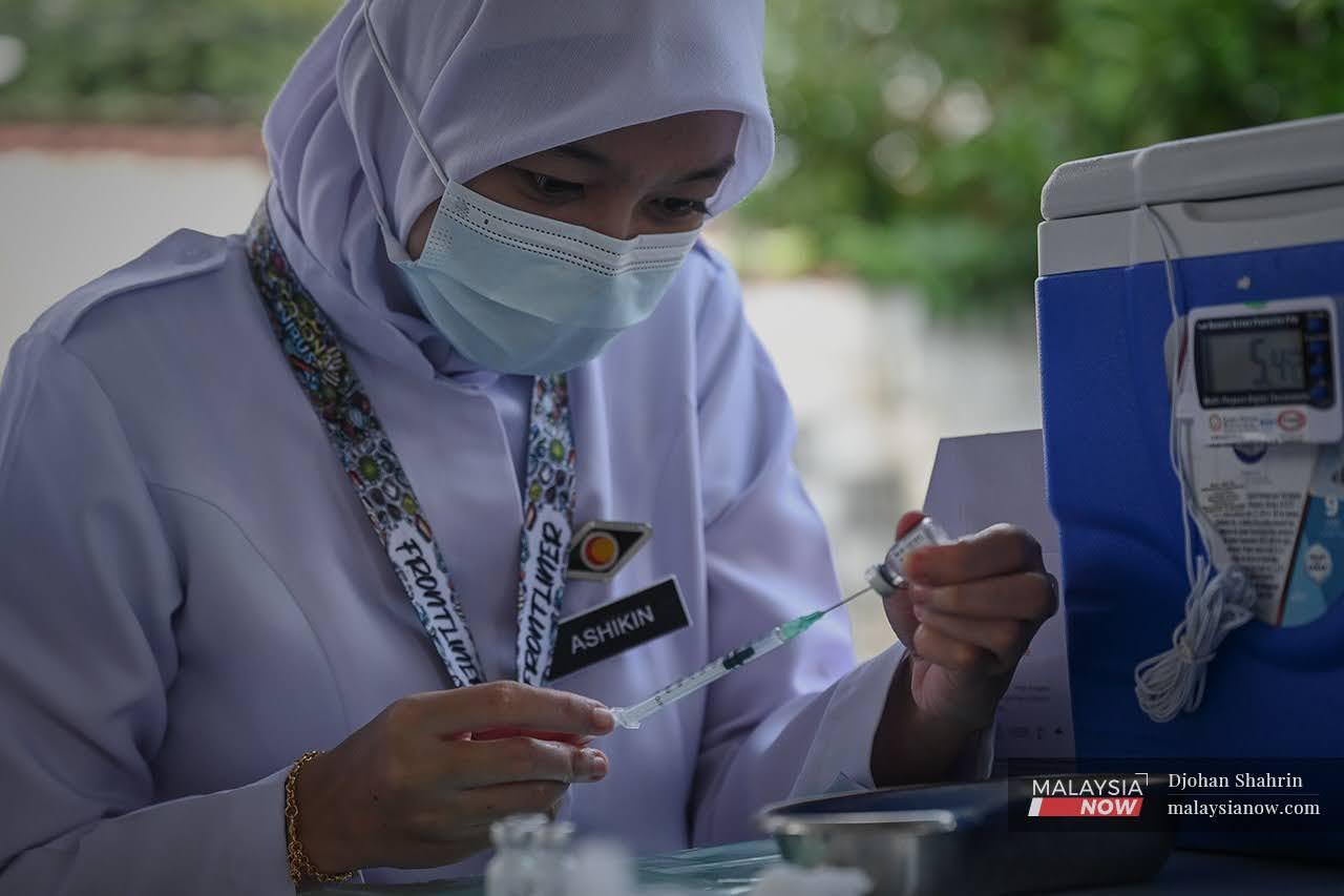 A nurse prepares a syringe of Covid-19 vaccine to be administered under the vaccine outreach programme to residents at a nursing home in Selangor.
