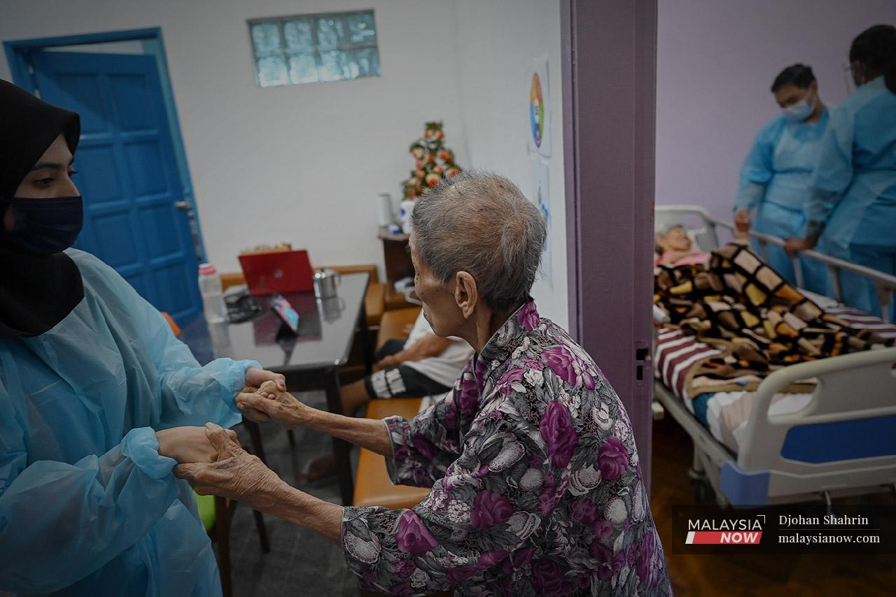 A nurse at the Heritage Senior Care Centre in Petaling Jaya helps a resident with her daily exercise around the house.