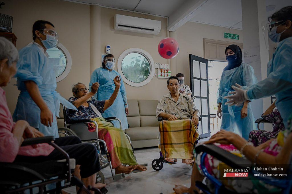 Warga emas bermain permainan bola plastik bagi mengisi waktu terluang di pusat jagaan.