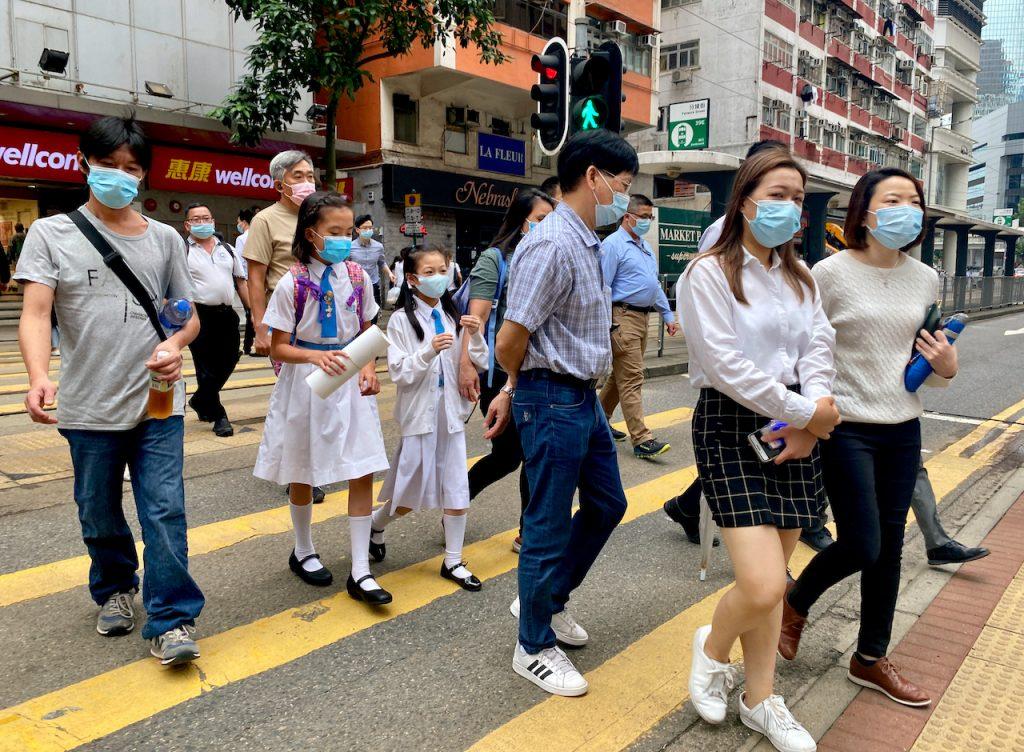 People wearing face masks to help prevent the spread of Covid-19 cross a street in Hong Kong, April 26. After six months, only 36% of the city's 7.5 million residents are fully vaccinated with two jabs while 48% have received one dose. Photo: AP