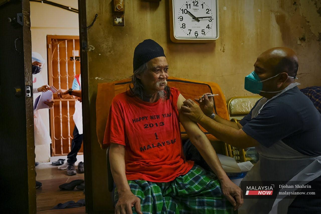 Doktor sukarelawan  menjalankan vaksinasi kepada seorang warga emas di Taman Dato Razali, Ampang dalam usaha vaksinasi rumah ke rumah Program Imunisasi Covid-19 Kebangsaan.