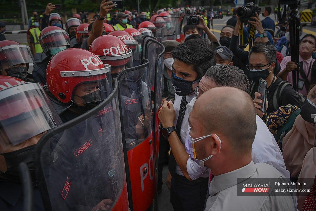 Muar MP Syed Saddiq Syed Abdul Rahman and Bagan MP Lim Guan Eng speak with police from the Federal Reserve Unit at a roadblock heading towards Parliament in Kuala Lumpur today.