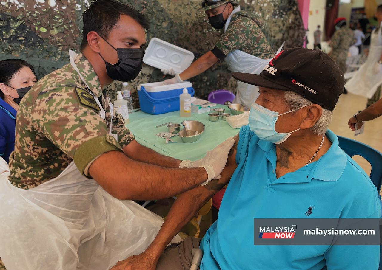 Dr Devandran Naidu administers a dose of vaccine to a senior citizen in a rural area in Sarawak.
