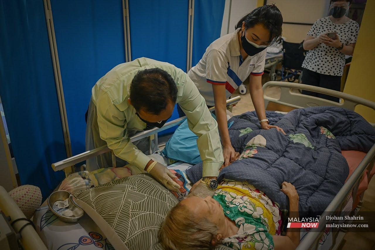 Petugas Klinik Kesihatan Petaling melakukan vaksinasi kepada seorang warga emas yang berada di katil ketika melakukan vaksinasi dari rumah ke rumah di Petaling Jaya.