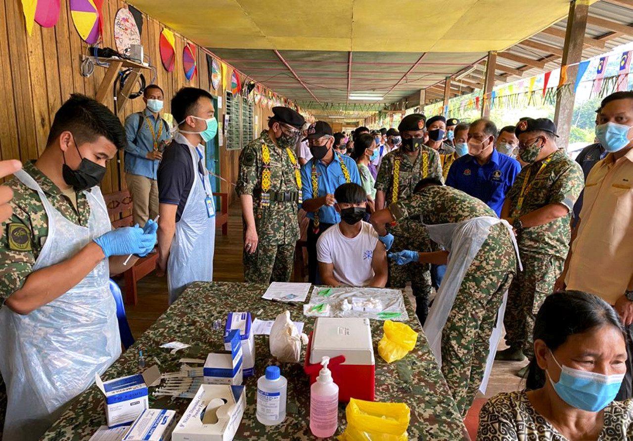 Sarawak Chief Minister Abang Johari Openg (second left) watches a health worker administer a dose of Covid-19 vaccine to a villager in Long Singut, Hulu Baleh, Kapit. Photo: Bernama