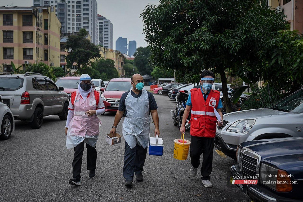 Doktor sukarelawan, Dr Mohammad Al-Imran Kassim bersama petugas Bulan Sabit Merah Malaysia membawa barangan vaksinasi ke rumah warga emas yang uzur di Taman Dato Razali, Ampang.