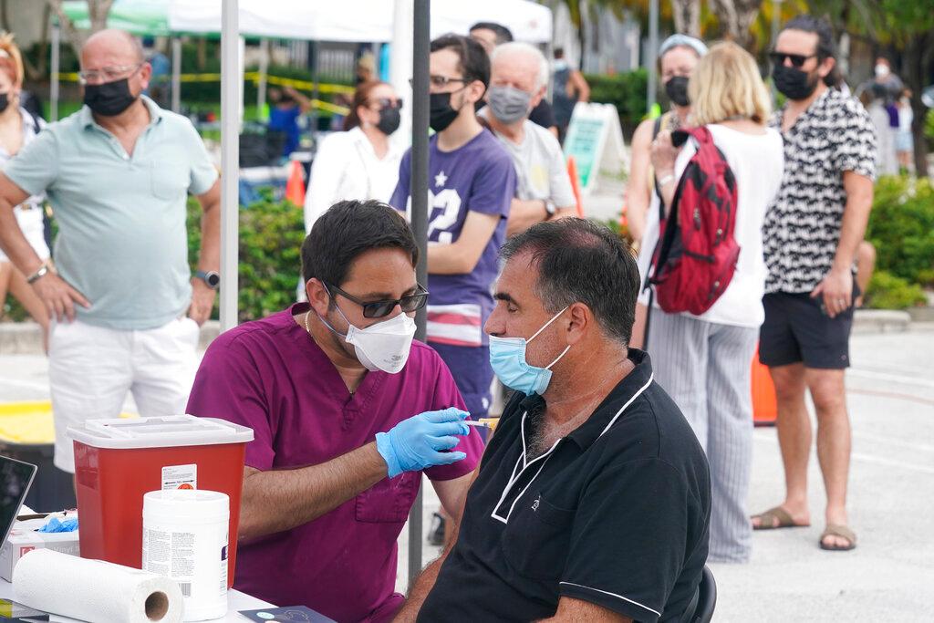 A man closes his eyes as he receives the Pfizer Covid-19 vaccine from a nurse, as others wait their turn, in Miami Beach, Florida, Aug 4. Photo: AP