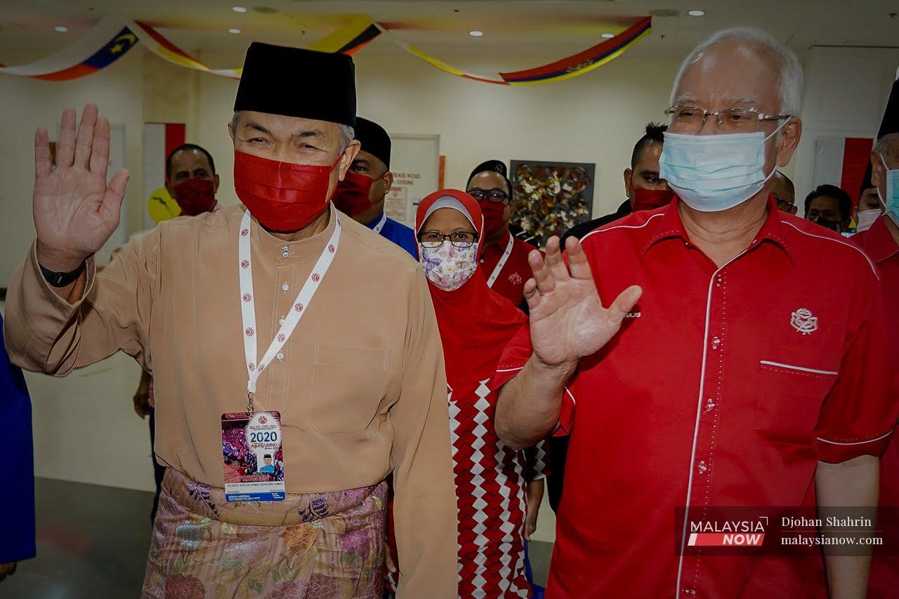 Bekas presiden Umno, Najib Razak bersama Presiden Umno, Ahmad Zahid Hamidi mengangkat tangan kepada pengamal media ketika hadir bagi mendengar perbahasan sayap-sayap Umno pada Persidangan Umno 2020 di Pusat Dagangan Dunia Putra.