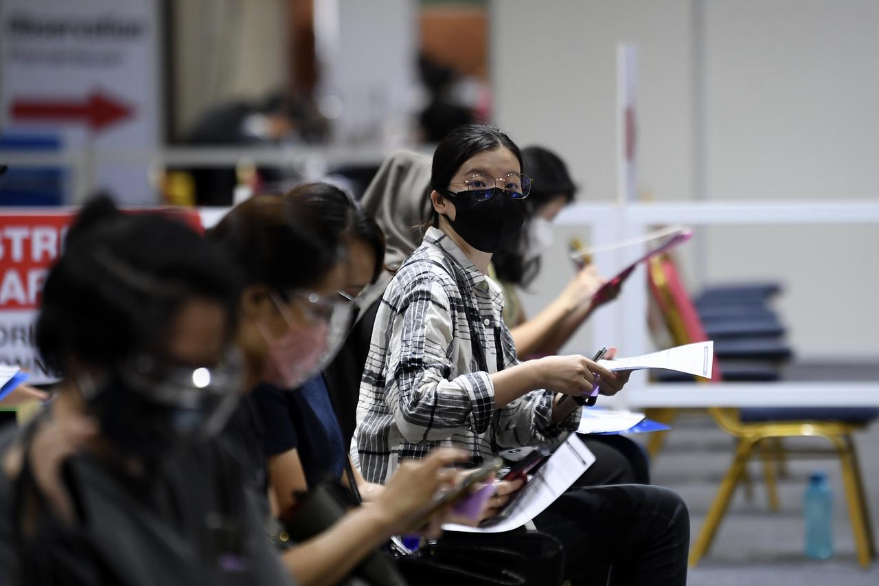 People fill in registration forms for walk-in vaccinations at the KLCC vaccination centre in Kuala Lumpur. Photo: Bernama