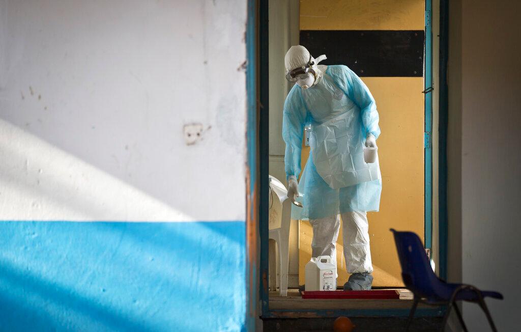 In this Oct 8, 2014 photo, a medical worker wearing full protective equipment decontaminates a cup used by a man being quarantined after coming into contact in Uganda with a carrier of the Marburg virus, a hemorrhagic fever from the same family as Ebola. Photo: AP