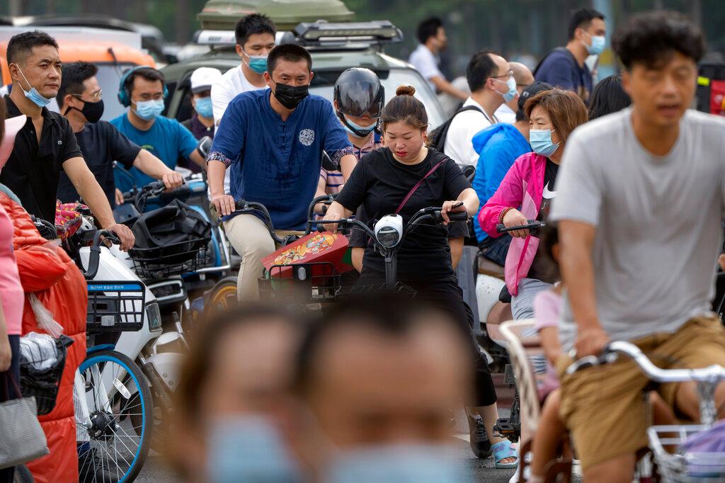People wearing face masks to protect against Covid-19 ride bicycles across an intersection during the morning rush hour in Beijing, Aug 4. Photo: AP