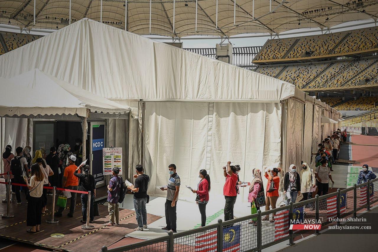 Penerima vaksin warga asing hadir secara walk-in ke pusat vaksinasi beratur menunggu giliran sebelum mendapatkan vaksin Sinovac di Stadium Bukit Jalil.