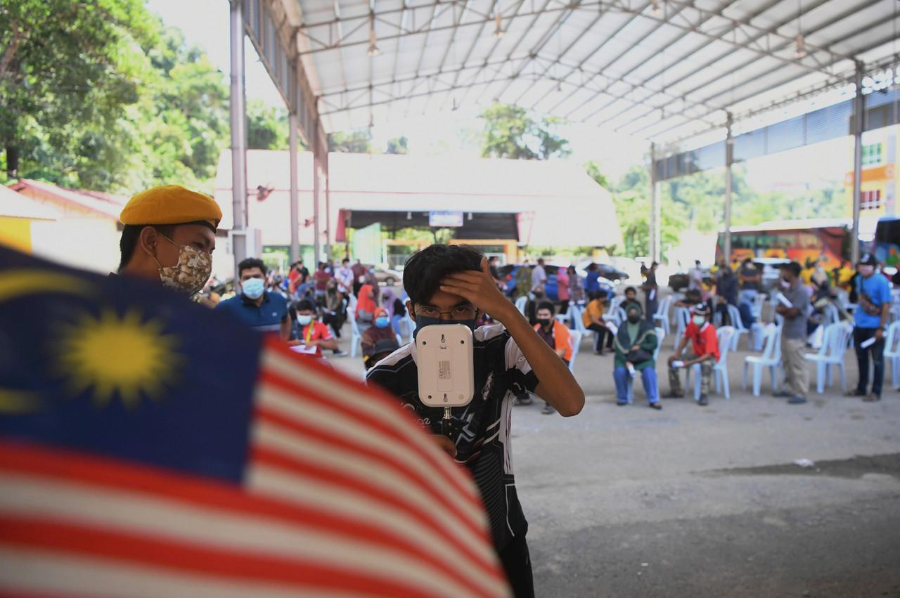 A man checks his temperature before being given a Covid-19 jab at the Dewan Jubli Perak Sultan Haji Ahmad Shah vaccination centre in Lipis. Photo: Bernama