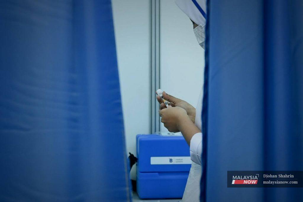 A health worker prepares a syringe of vaccine at the Axiata Arena vaccination centre in Bukit Jalil, Kuala Lumpur.