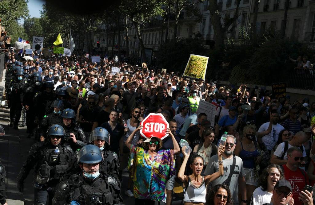 Police officers accompany demonstrators as they march during a protest in Paris, Aug 14. Protesters are rallying in Paris and other parts of France to show their opposition to France's introduction of a Covid-19 passes to access restaurants, hospitality venues, cultural sites and domestic travel. Photo: AP