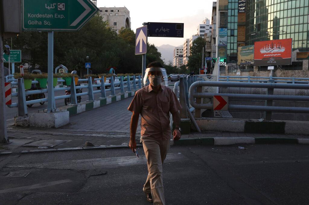 A man wearing a protective face mask and shield to help prevent the spread of the coronavirus crosses a street in central Tehran, Iran, Aug 8. Photo: AP