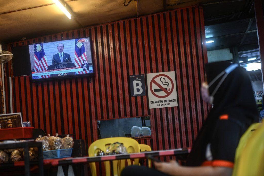 Seorang wanita menyaksikan perutusan bekas perdana menteri Muhyiddin Yassin berucap semalam. Gambar: Bernama