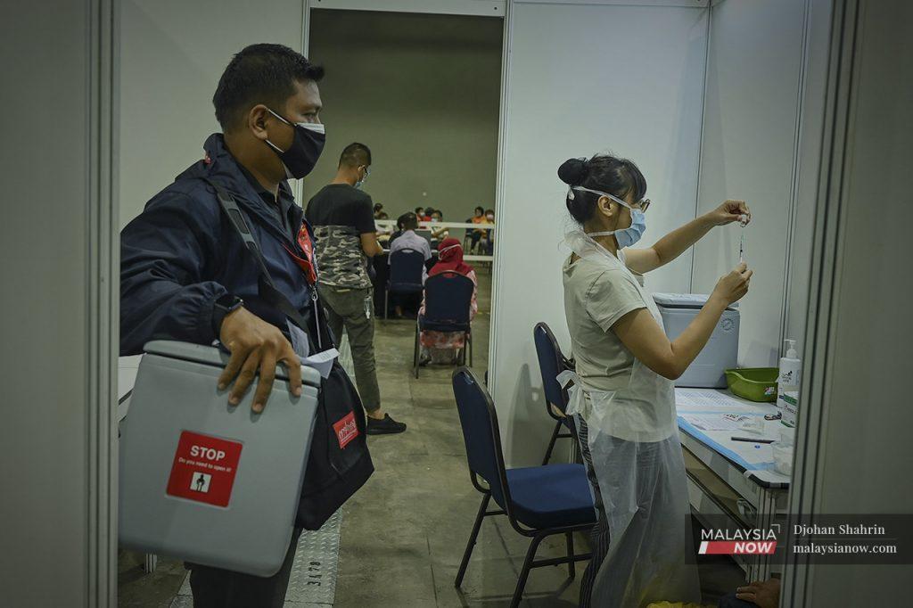 A health worker brings in a fresh supply of vaccine at the Mitec vaccination centre in Kuala Lumpur.