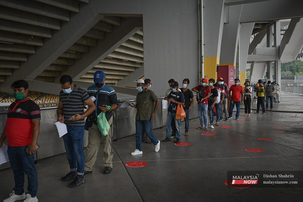 Penerima vaksin warga asing hadir secara walk-in ke pusat vaksinasi menunggu giliran sebelum mendapatkan vaksin Sinovac tanpa janji temu di Stadium Bukit Jalil.